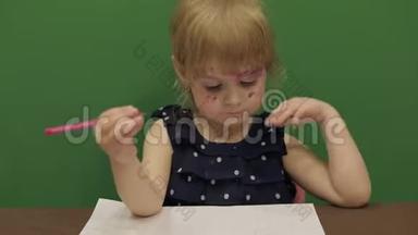 女孩在桌子边画画。 快乐的三岁女孩。 可爱的女孩微笑。 棕色的眼睛。 一个漂亮的小孩，3-4岁的女孩
